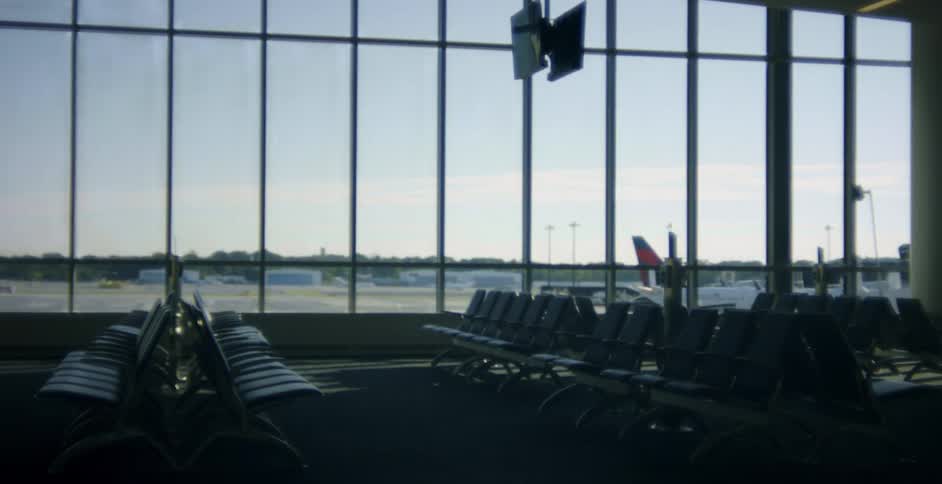Windows of empty airport terminal show trees bordering tarmac