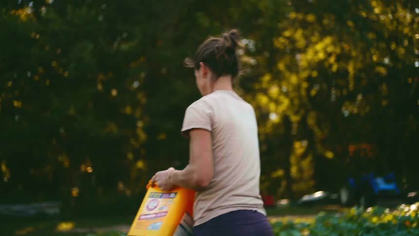 A woman walks through a field planting seeds taken from a bucket