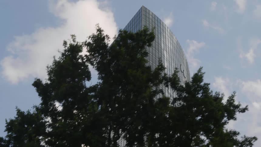 A skyscraper with mirrored windows dwarfs the surrounding buildings