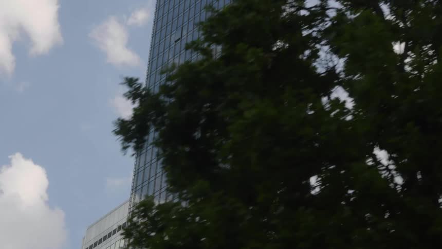 A tall building next to other buildings near trees