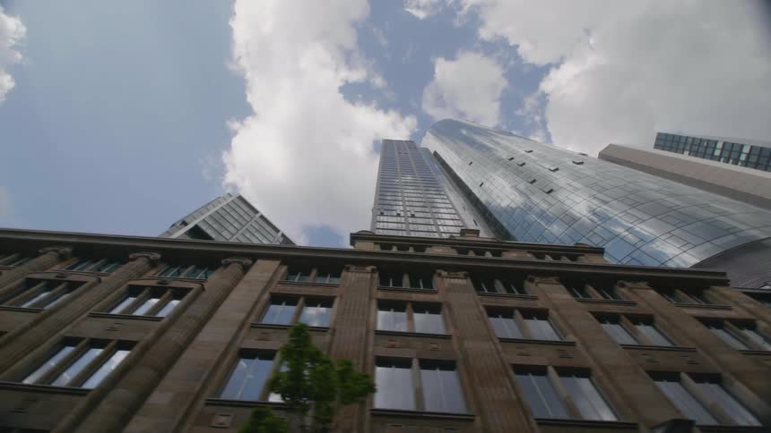 Windows of skyscrapers reflect overhead clouds