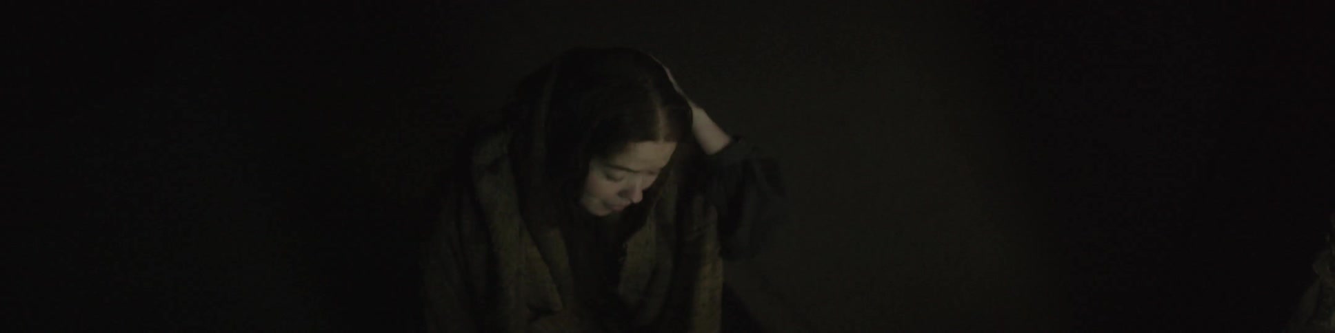 A woman removing the hood of a cape from her head