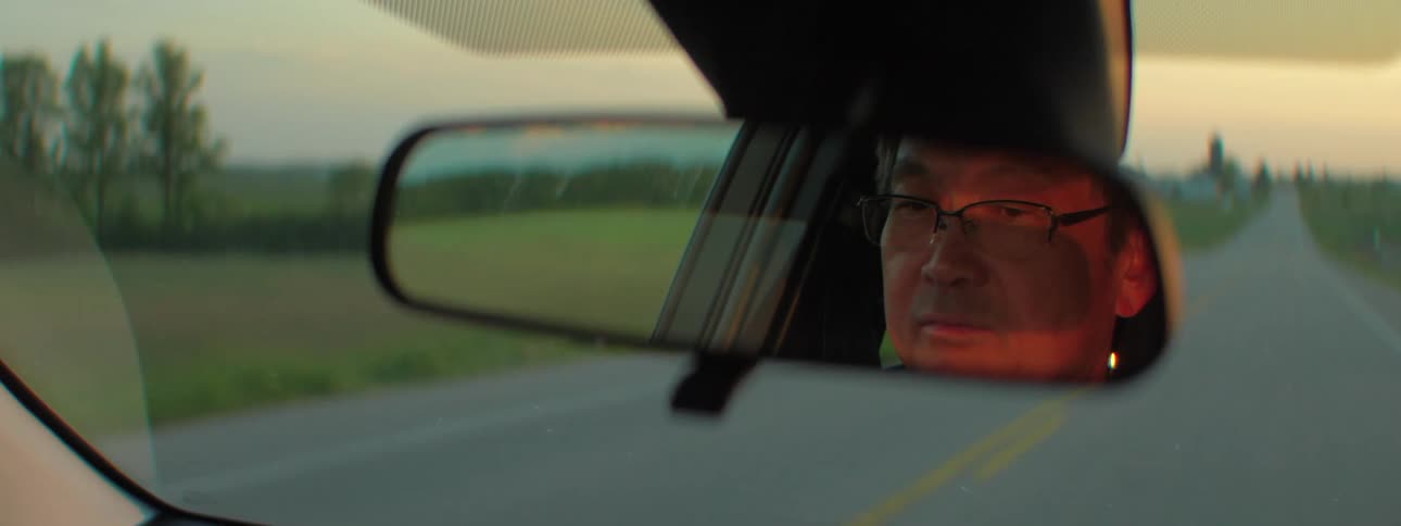 An asian man drives down a road toward the horizon