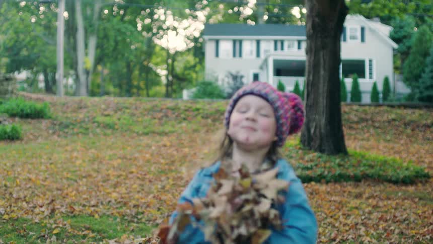 Child tossing leaves at camera