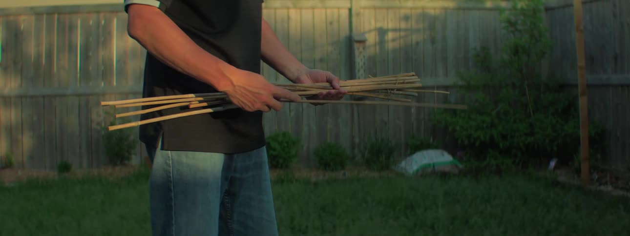 A man in his back yard puts stick in to the ground
