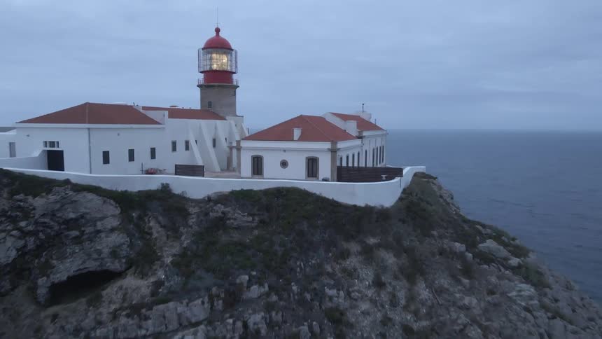 Lighthouse on top an ocean side cliff shines a beacon of light