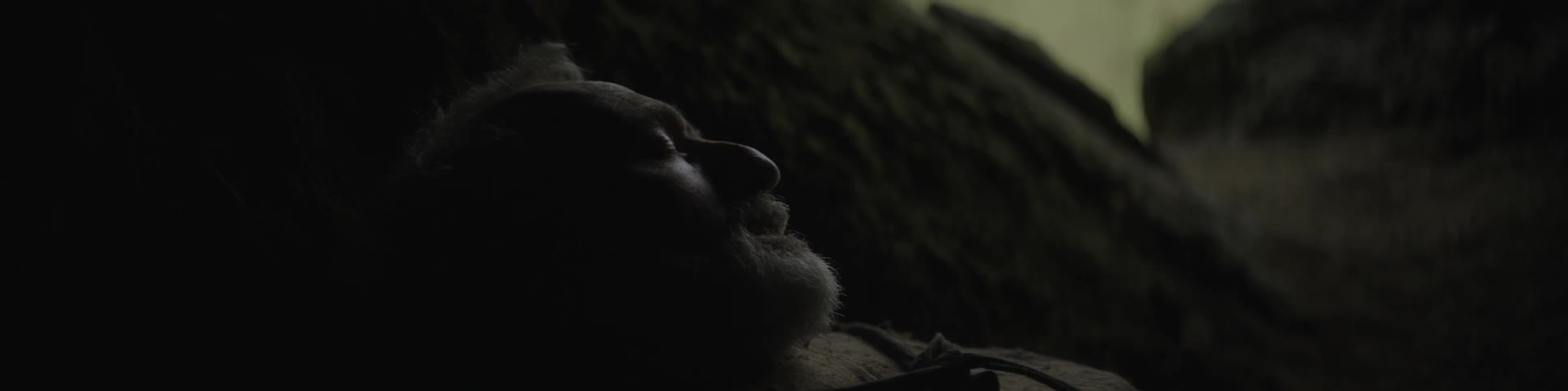 An elderly man resting in a cave