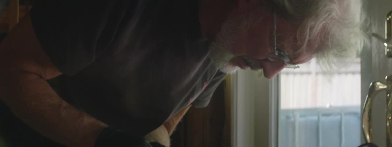 Man leans over as he works inside near golden handle