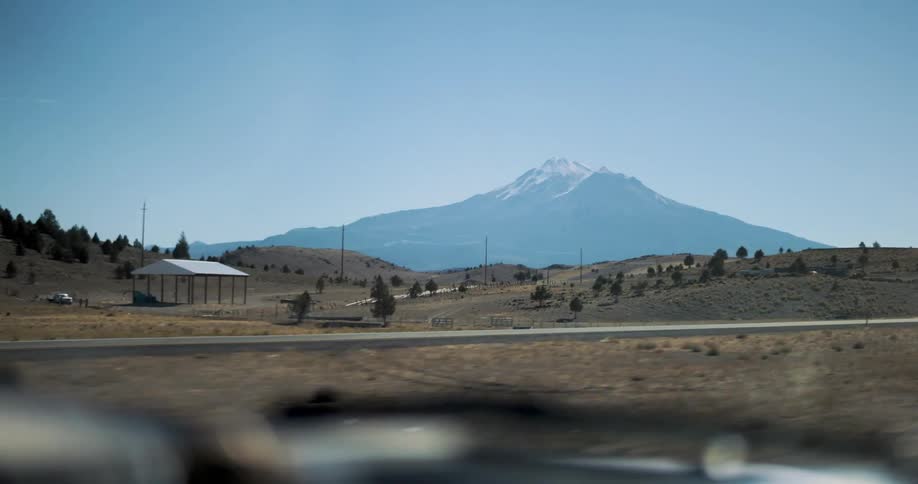 Inside a moving car filming a mountain on the side of the road