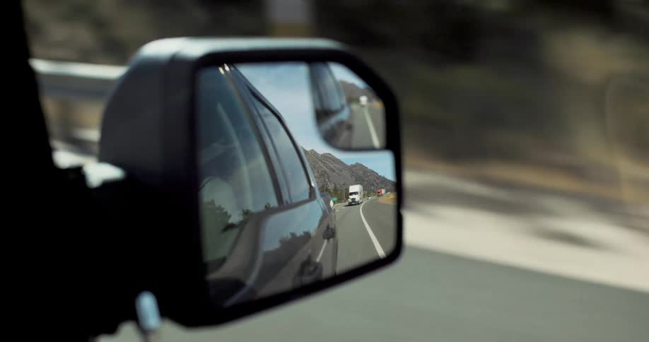 Cars driving on a highway through a rear view mirror