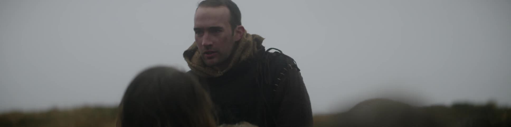 Man in cloak talking to people standing below him