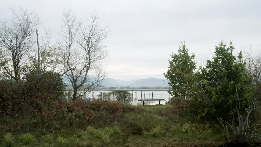 Mist obscures mountains across water from pier