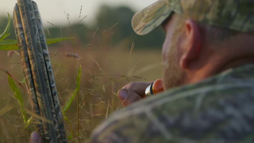 A man uses a bird call in a field
