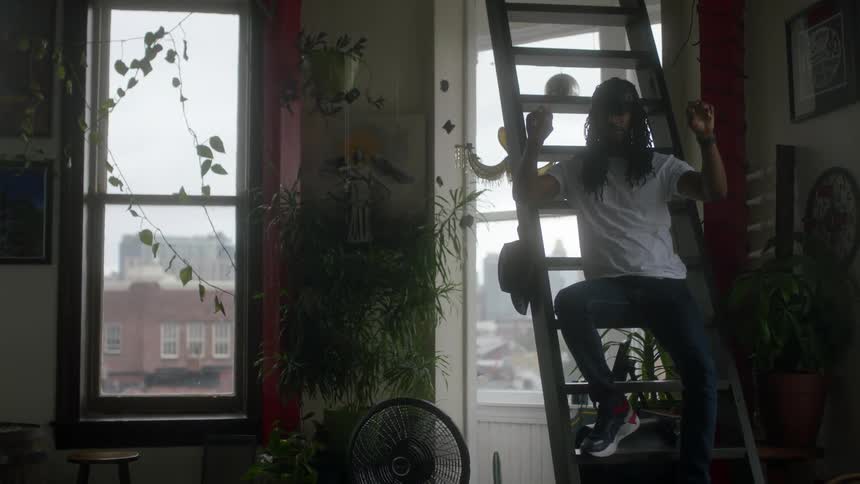 A man is wearing a virtual reality headset while sitting on the stairs and moving his arms