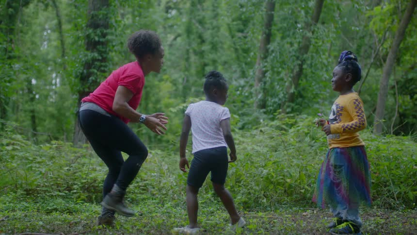 Woman playing a game with children out in a forest