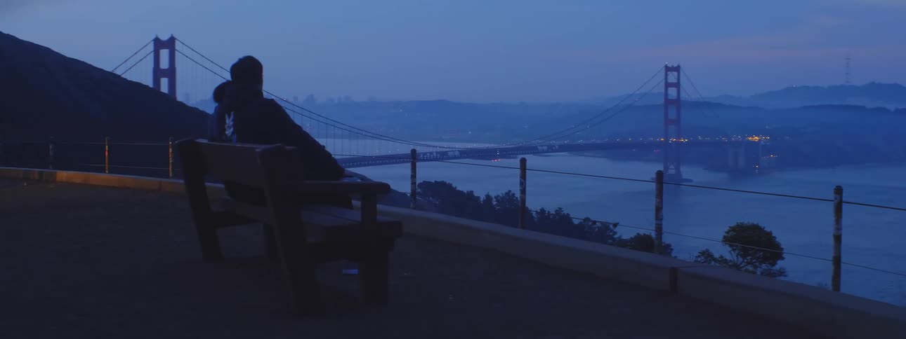 Man sitting on a bench staring off at the golden gate bridge