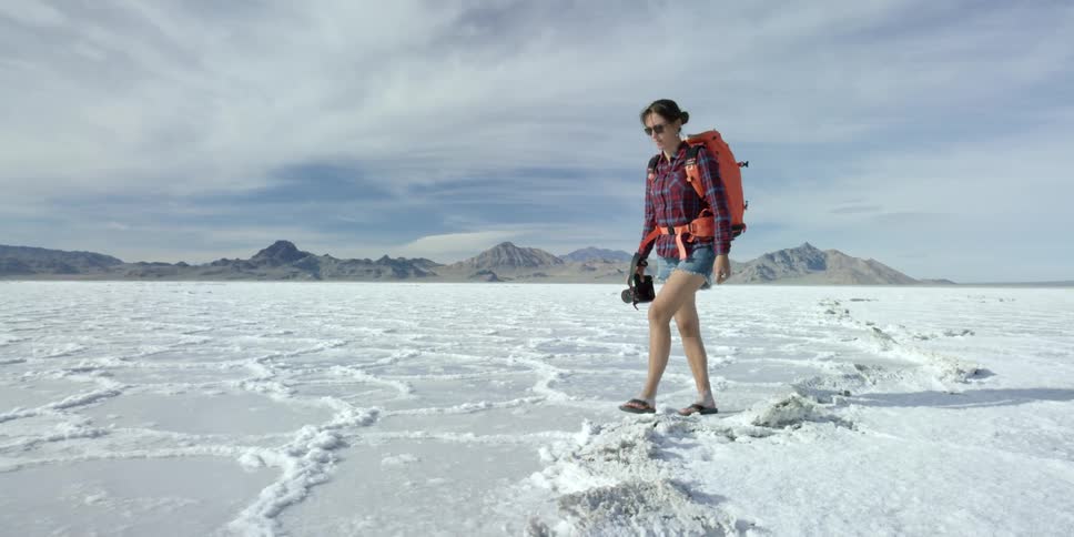 A woman is walking along a field with ice and snow