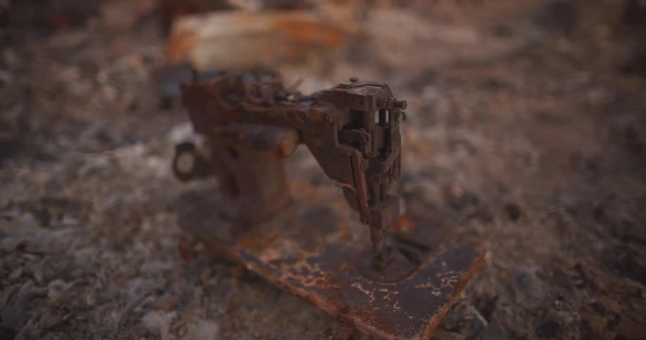 Old rusted metal machine at daytime on a floor covered in rocks and gravel