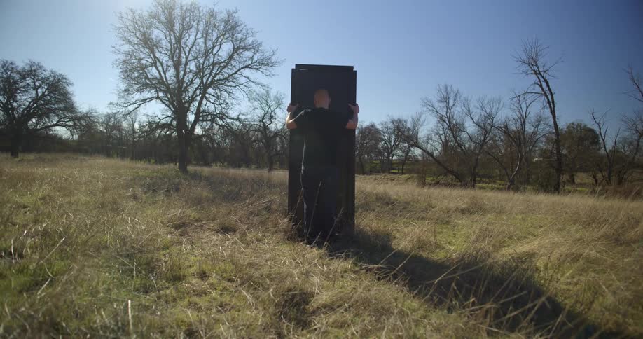 A man is placing a box on the field
