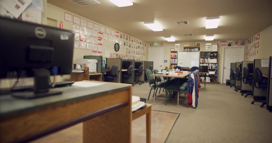 A long table sits in the center of a computer lab