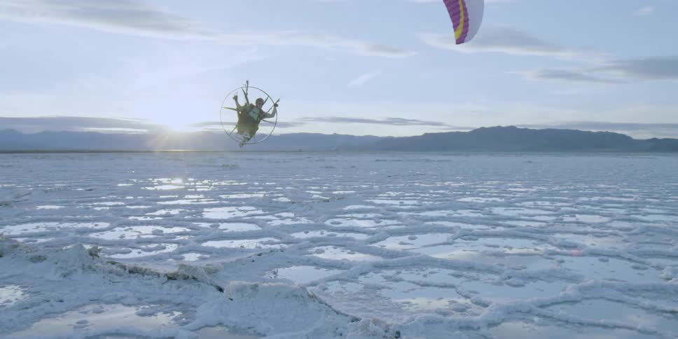 A person is parasailing over a ice covered body of water