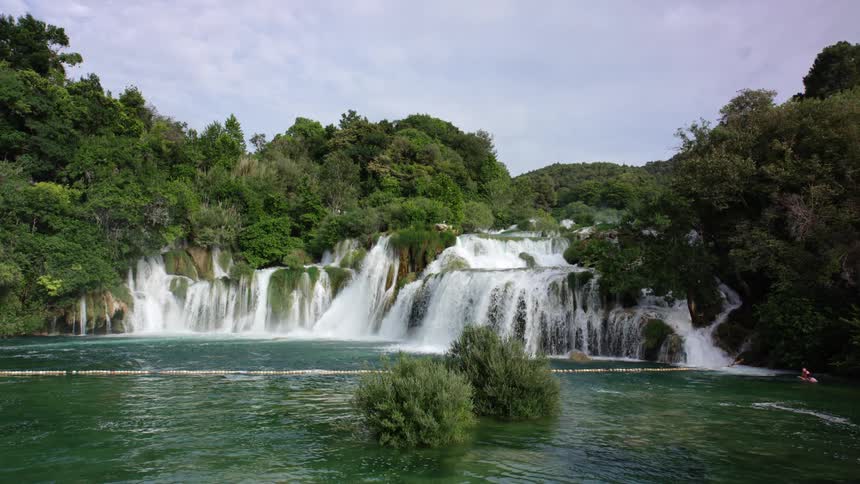 Waterfall flows into river with trees all around