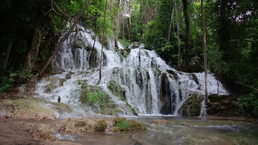 A waterfall with green trees all around