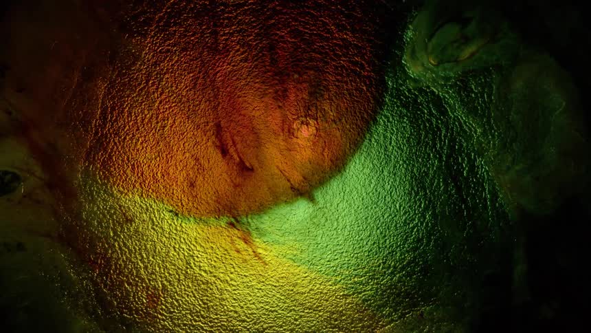 Water spreads outward over green orange and yellow lights until a hole opens up and reverses the waters direction