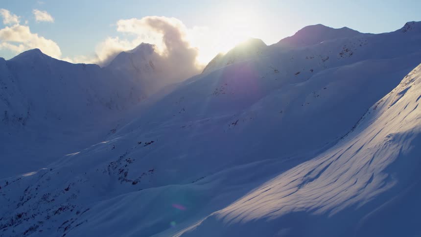 Aerial view of the sun setting behind the snow capped mountains