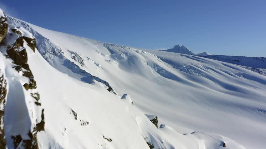 Snow covered mountains on a sunny day with another mountain peak in shadow in the background