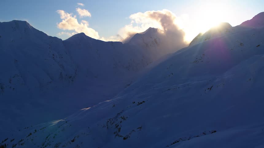 The sun goes down behind the snowy mountains