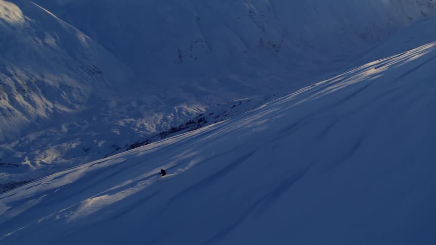 A skier skiing down a snowy mountain side