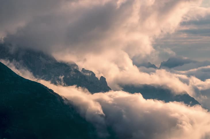 Clouds moving and pouring downwards at day time at the top of mountains