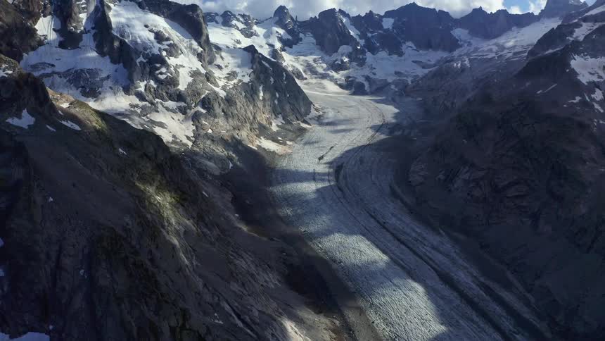 The sun shines over a road between mountains