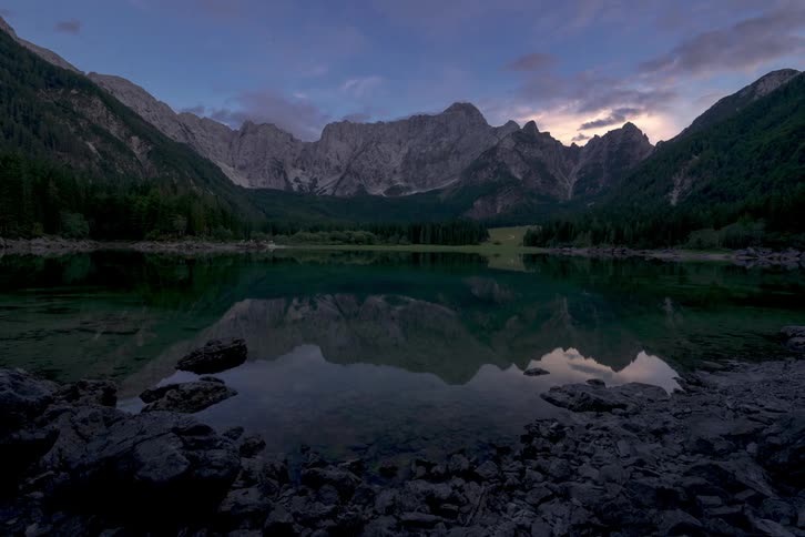 Clouds in the sky pass over a lake between mountains