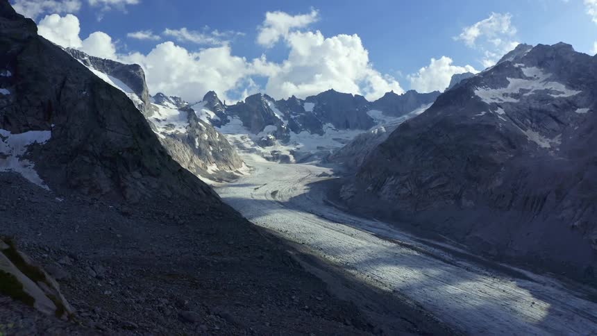 Snow covered mountains near large clouds and the sky