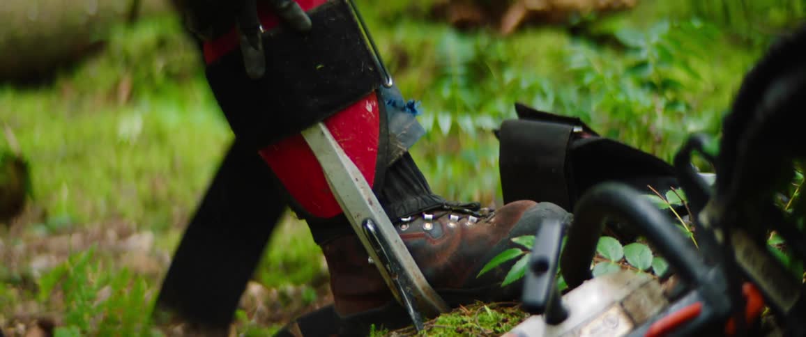 Man putting his shoe down on the ground to strap on gear on a small green slope outdoors at daytime