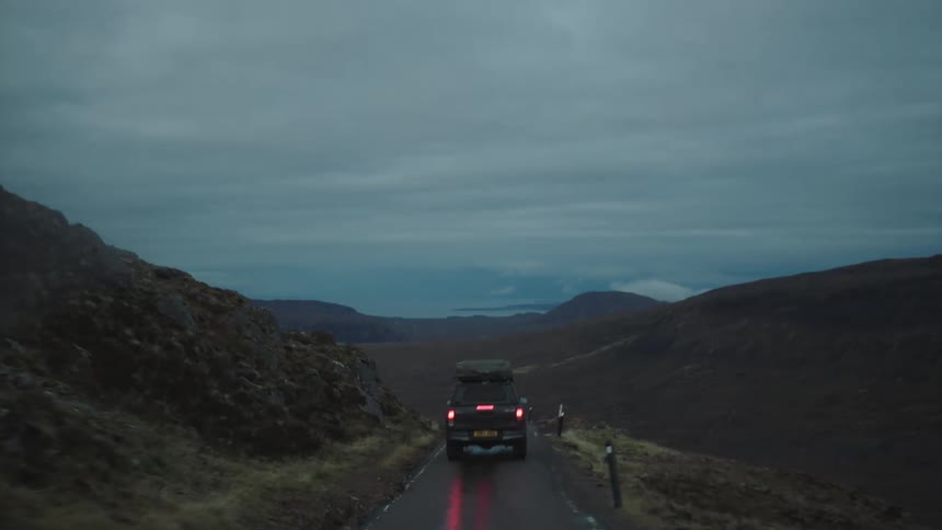 Four wheel drive car drives on wet country road in the hills on a cloudy day