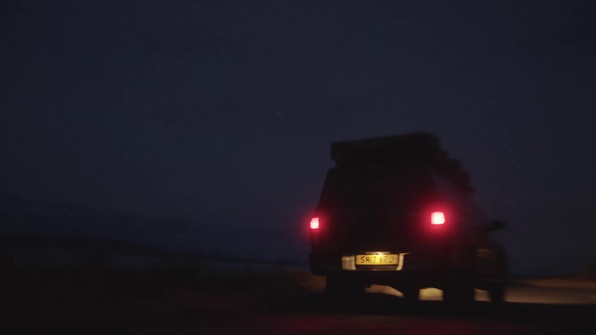 A truck traveling on a road at night with bright headlights blaring