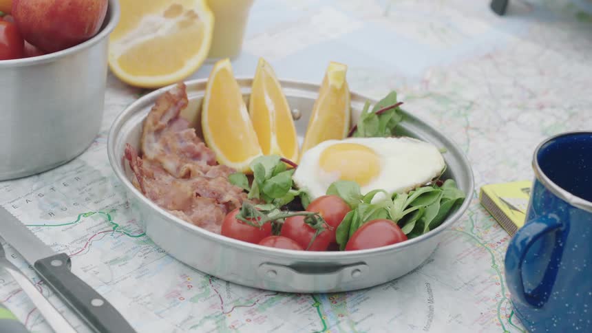 Person sets breakfast on table covered with map