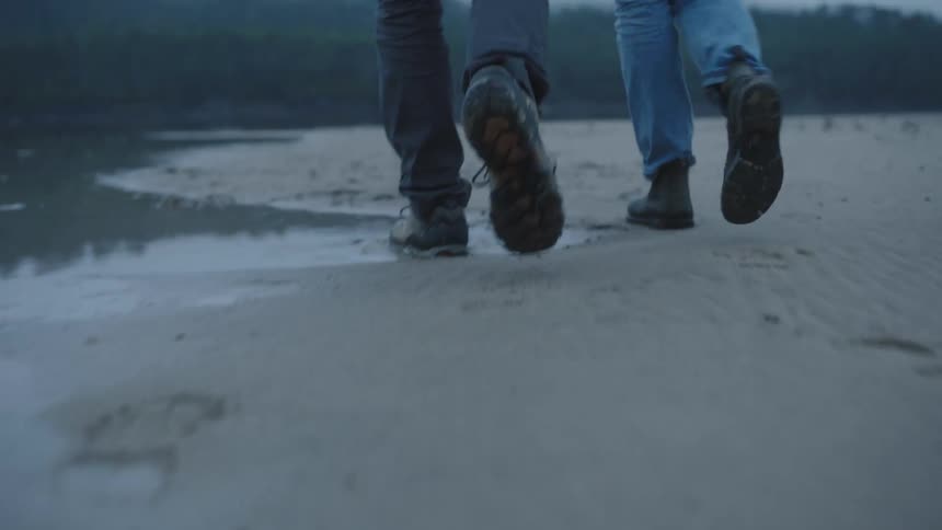 A man and woman walk along the beach