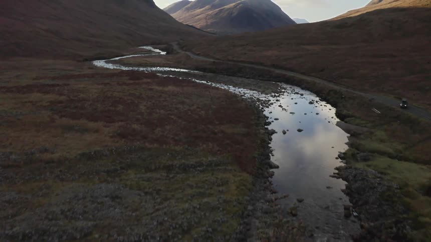 Stream of water leading up towards a mountain range in a canyon