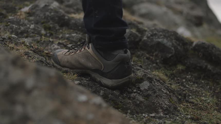 A person is walking on the rock covered ground