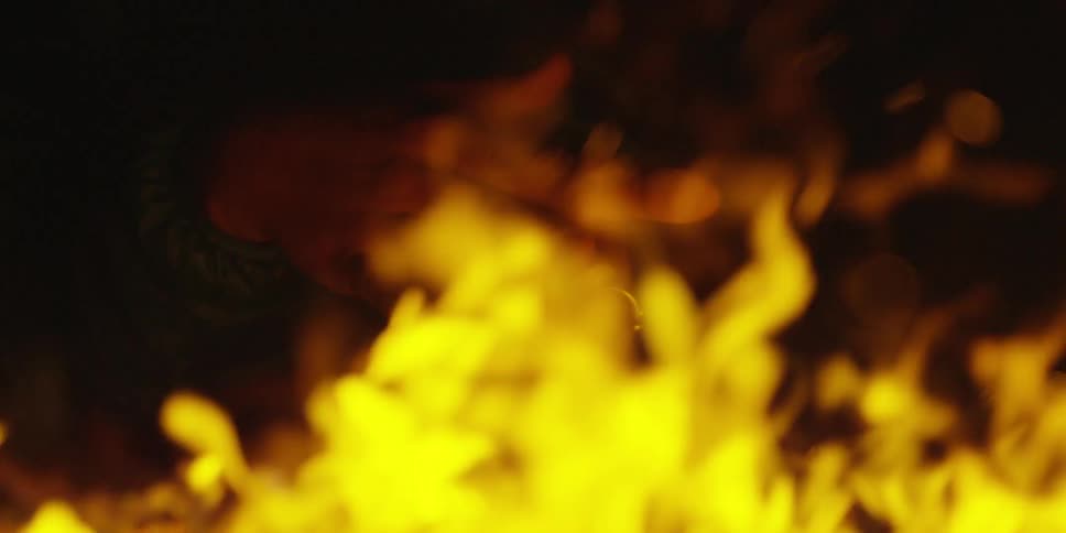 A person is warming their hands near a campfire at night