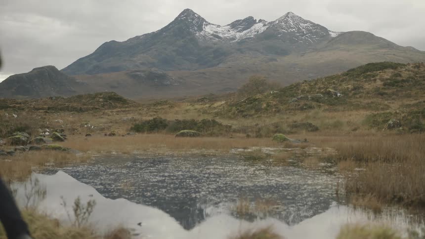Man and woman jog past ice and frozen pond with mountain on horizon