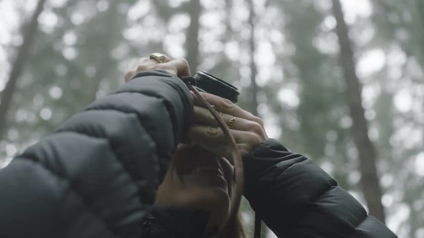 A woman takes pictures in a forest