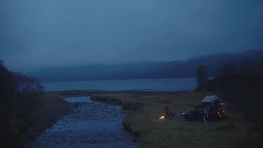 A campsite near a river with a campfire at night