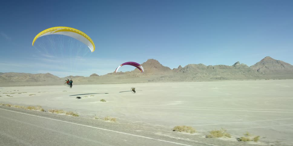 People parasailing over a desolate sandy region