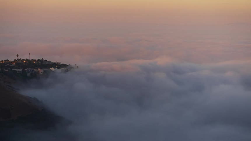 Light brightens heavy fog surrounding town sitting near promontory