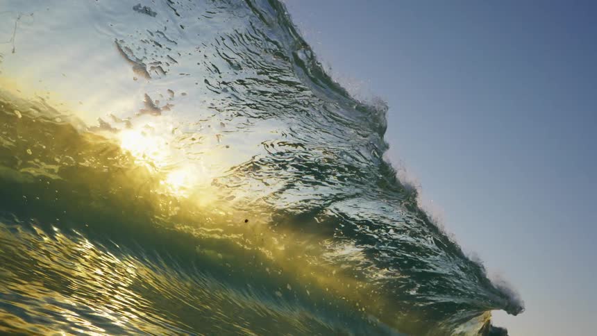 Ocean wave breaks against the beach at dusk